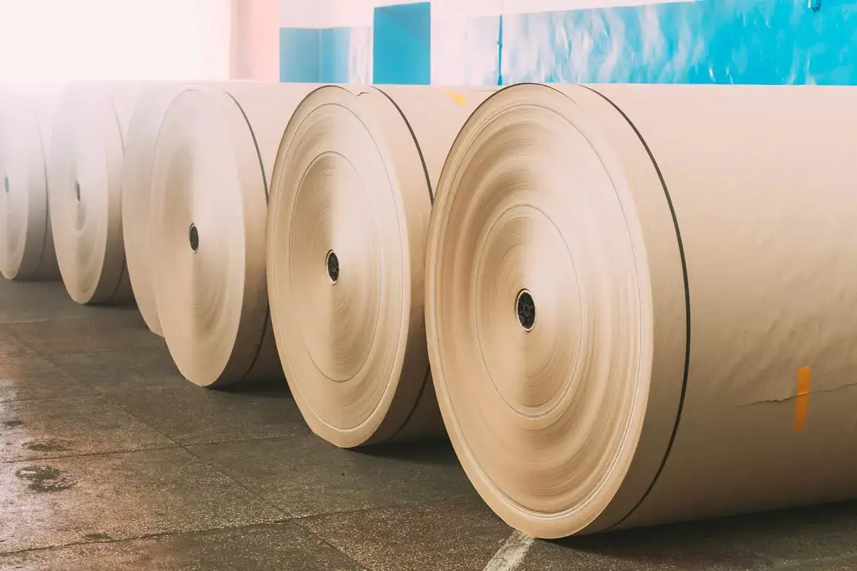 Rollos de papel offset apilados en un almacén, listos para la impresión.